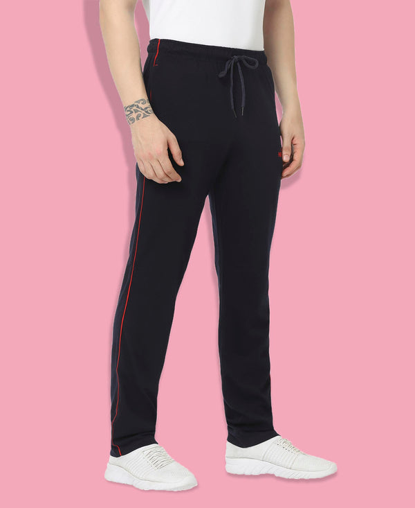 Person wearing black pants with red stripes on a pink background