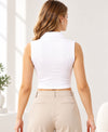 Woman wearing a white sleeveless top and black pants against a pink background
